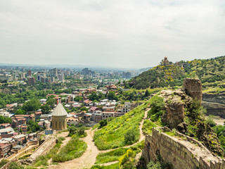 Narikala fortress with footpaths, ancient walls and st. Nicholas church seen inside of it, and the city of Tbilisi expanding behind.
