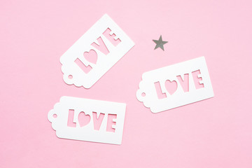 White gift tag with inscription love, on a pink background, decorated with silver stars, festive concept. 