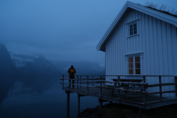 Traveler man with a yellow backpack standing on the background of night Lofoten Reine