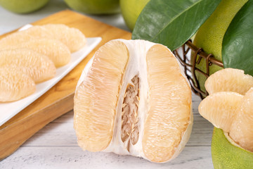 Fresh peeled pomelo, grapefruit, shaddock with green leaf on bright wooden plank table. Seasonal fruit near mid-autumn festival, close up, copy space