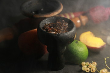 bowl with tobacco for hookah. fruits on a black background. smoke hookah