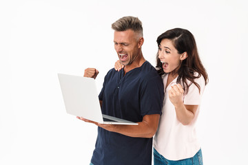 Fototapeta premium Cheery positive adult loving couple isolated over white wall background using laptop computer.