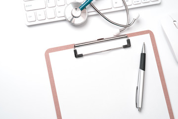 Doctor diagnoses concept - stethoscope on computer keyboard with medical record case and pen on white working table. Top view, flat lay, copy space