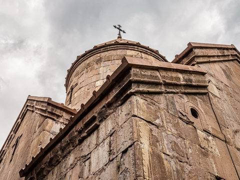 Domed top part of a main church of an ancient Goshavank monastery located in the village of Gosh in the Tavush Province of Armenia, photographed against dark cloudy sky.