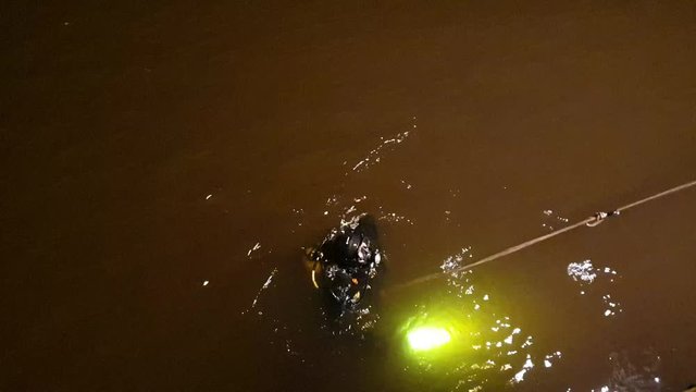 A diver is looking for a drowned man. The search for the drowned. Diver at night.