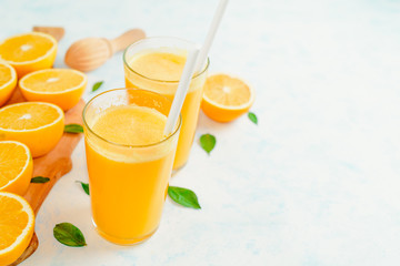 Orange juice and orange fruits with green leaves on white background.