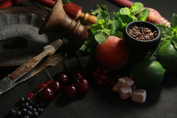 bowl with tobacco for hookah. fruits on a black background. smoke hookah