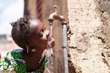 Joyful Black Child Drinks Fresh Water from a Tap