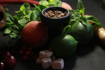 bowl with tobacco for hookah. fruits on a black background. smoking hookah