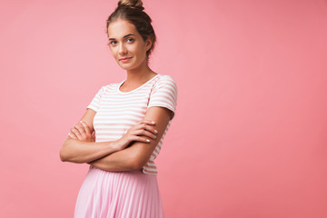 Image of alluring beautiful woman wearing striped clothes smiling at camera and standing with arms crossed