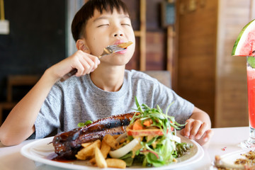 Young boy eat pork steak