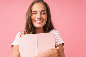 Fototapeta na wymiar Image closeup of content pretty woman smiling at camera while hugging her diary book