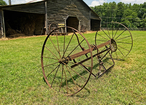 A Rusty Plow by an old Barn on a farm