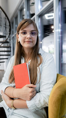 Portrait of pretty young  woman student smiling at camera with notebook. Student and tutoring education with education concept.