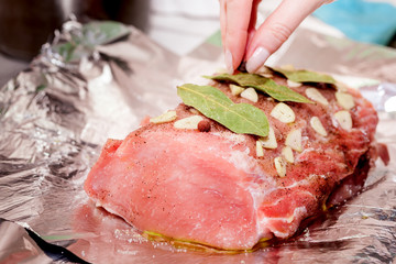 girl puts seasonings on a piece of raw pork on foil