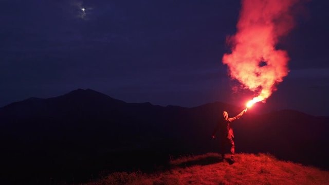 The man with a firework stick standing on a night mountain