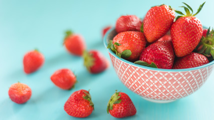 bright printed bowl of fresh strawberries on blue wooden background