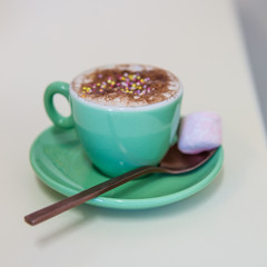 Babycino drink with sprinkles and marshmallow.