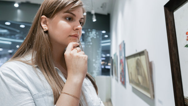 Young Woman Visiting Art Gallery Lifestyle Concept. Girl looking at modern painting in art gallery