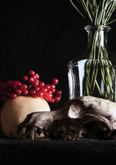Memento Mori. Still life of a skull, viburnum and a glass bottle with a bouquet on a dark background