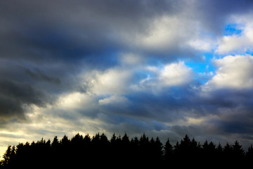 Dark gray dramatic sky with large clouds and sunlight.