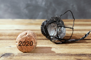 Champagne cork on brown wooden background with numbers 2020. Concept of the New Year.