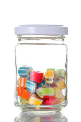 a glass jar half  full of colored candies with isolated on white background with clipping path and copy space for your text