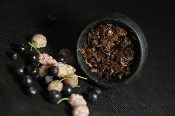 Obraz na płótnie Canvas bowl with tobacco for hookah. fruits on a black background