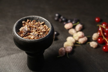bowl with tobacco for hookah. fruits on a black background