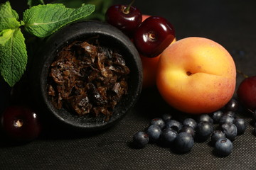 bowl with tobacco for hookah. fruits on a black background. smoke hookah