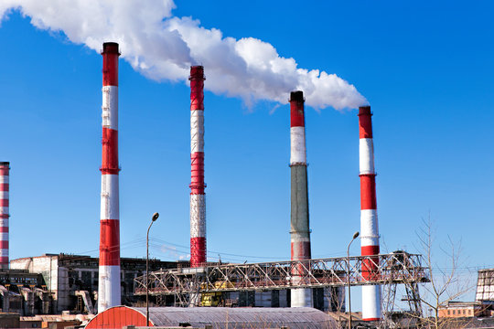 Factory plant smoke stack over blue sky background. Thermal condensing power plant. Energy generation and air environment pollution industrial scene