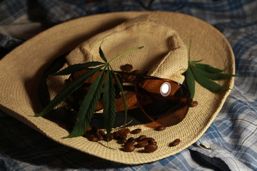 straw hat, glasses and leaves of marijuana on a black background