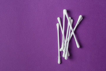 White plastic cotton swabs on purple background