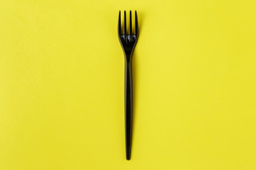 Black plastic fork on yellow background