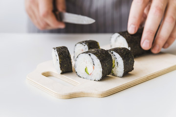 Person slicing sushi wrap on cutboard