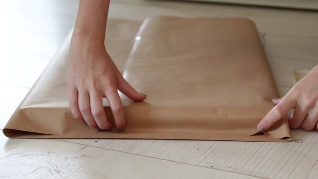 Female hands wrap a gift in craft gift paper. Preparation for a new year, birthday or christmas