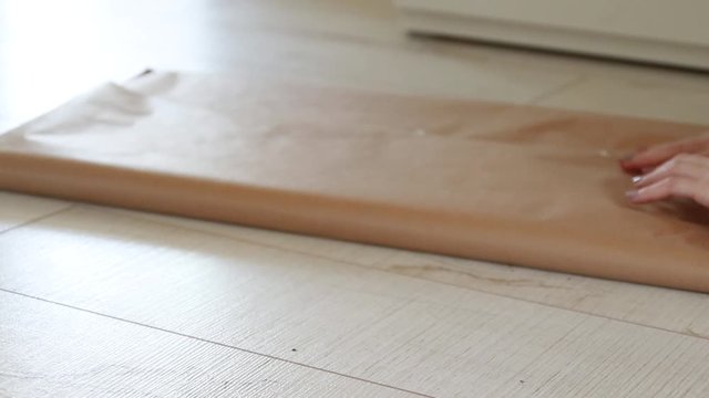 Female hands wrap a gift in craft gift paper.