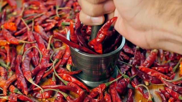 Slow motion video of chef pounding red chilies (lal mirch - Indian spice) in mortar. 