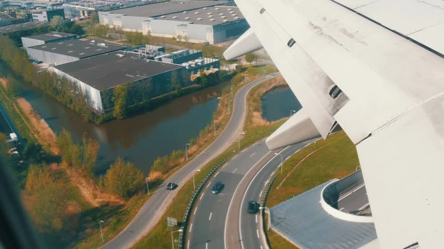 The plane is preparing for landing. Flying over water channels, greenhouses, farms with solar panels, houses, the route of the city of Amsterdam, Holland, the Netherlands