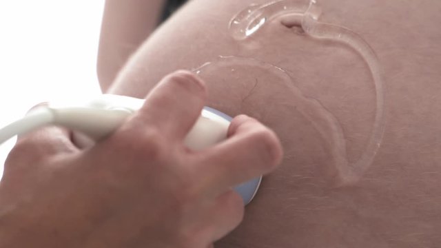 Ultrasound scanner on a pregnant woman's belly, close up