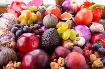 Background of fresh vegetables and fruits. Purple eggplant, plums, figs, apples, avocado, grape, hazelnut, sweet pepper, tomato and garlic. Purple and red food. Different vegetables on the table.
