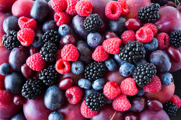Ripe blackberries, blueberries, plums, pink grapes, raspberries. Mix berries and fruits. Top view. Background berries and fruits. Various fresh summer fruits. Black-blue and red food.
