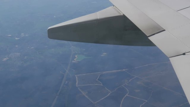 The plane flies over the fields of Europe, the wing of the plane in the porthole