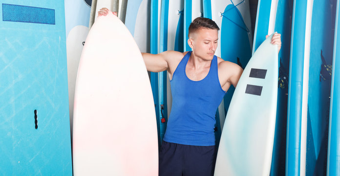 man choosing surf equipment in surf club