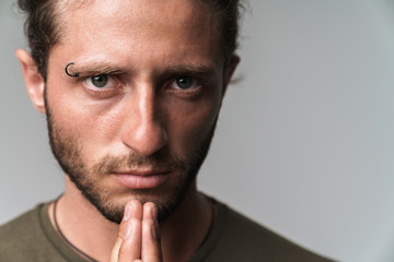 Concentrated young man standing isolated over gray