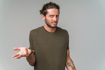 Confused young guy wearing casual clothing standing isolated