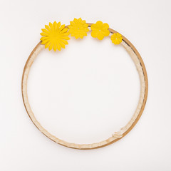 Yellow flowers decorated on circular wooden frame on white backdrop
