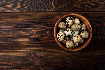 Quail eggs on dark wooden background.