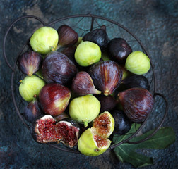 figs in a basket on a dark background. Large, small purple figs and white figs
