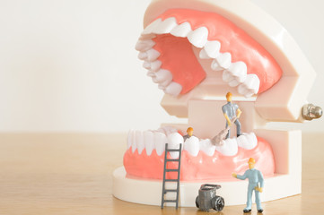 Miniature worker model cleaning teeth for dental clinic, good health care demonstrate how to clean, fix, taking care of teeth